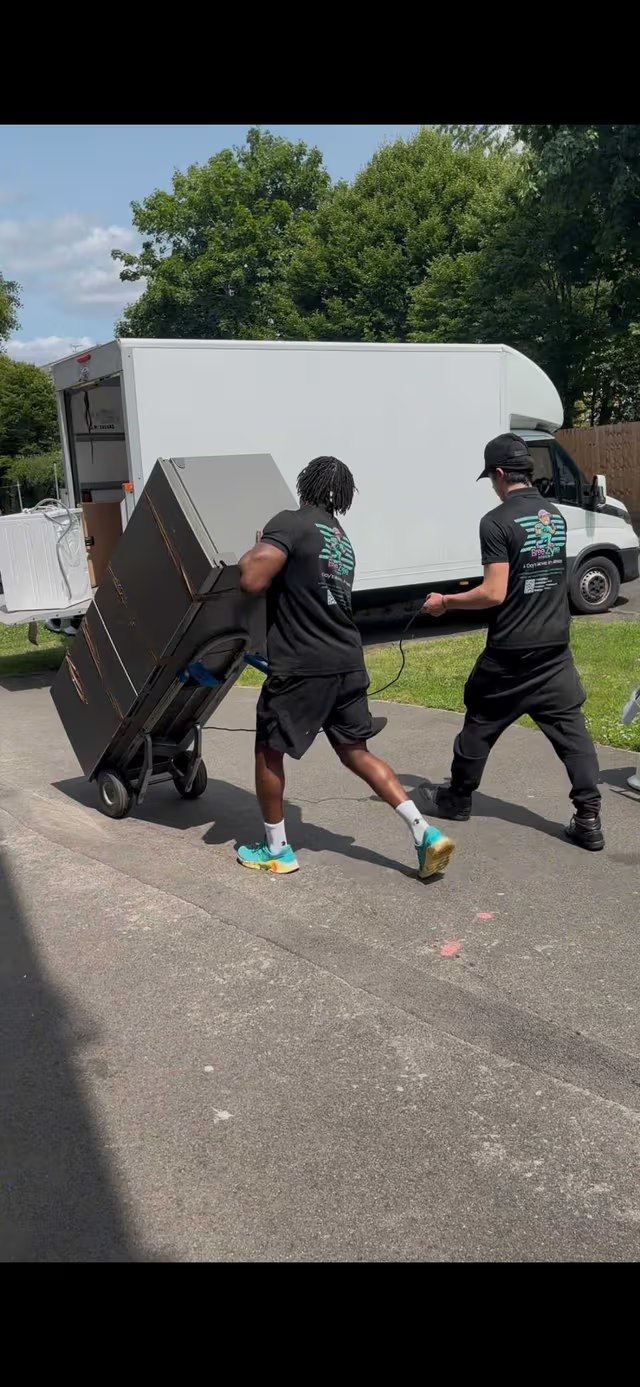 Team members using professional dolly to move large appliance
