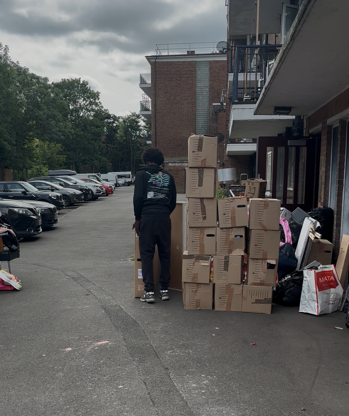 Team member organizing multiple stacks of moving boxes in residential complex